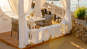 Decoração de casamento na praia no Algarve com letras gigantes LOVE junto a uma pérgola de madeira e areia.