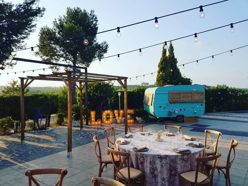 Decoração de um jardim para casamento com uma mesa redonda montada e letras gigantes iluminadas com a palavra LOVE ao fundo.