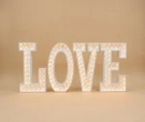 Letras gigantes luminosas brancas que formam a palavra LOVE acesas com lâmpadas embutidas de luz quente.