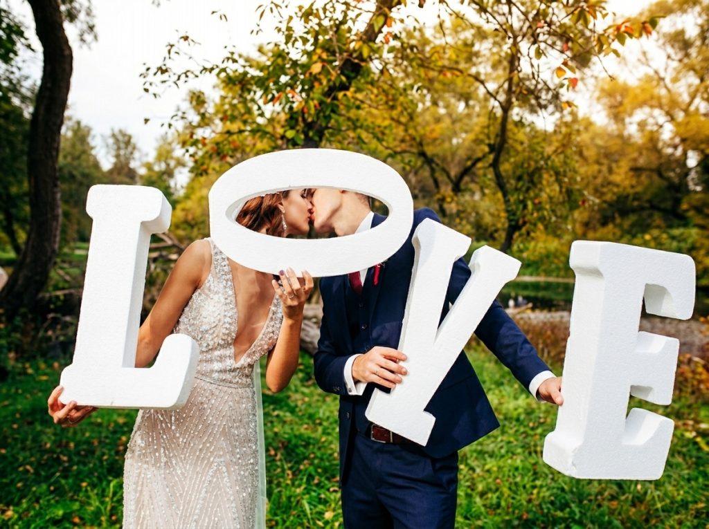Decoração de casamento ao ar livre na praia com letras gigantes LOVE brancas integradas numa pérgola de luxo.