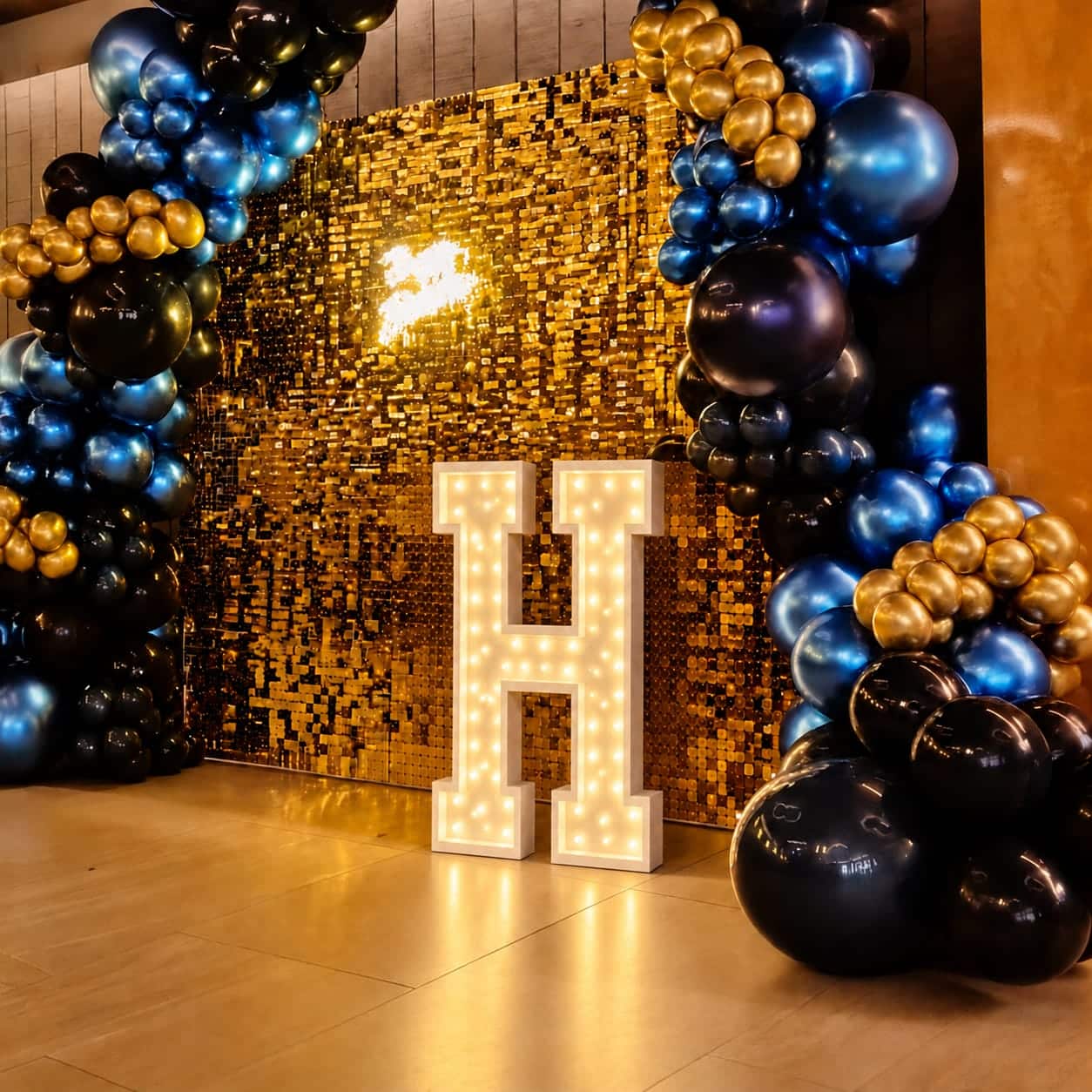 Letra H luminosa numa festa com decoração dourada e balões